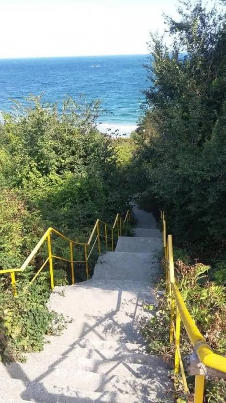 Бетонни стълби с жълти парапети, които слизат към морето